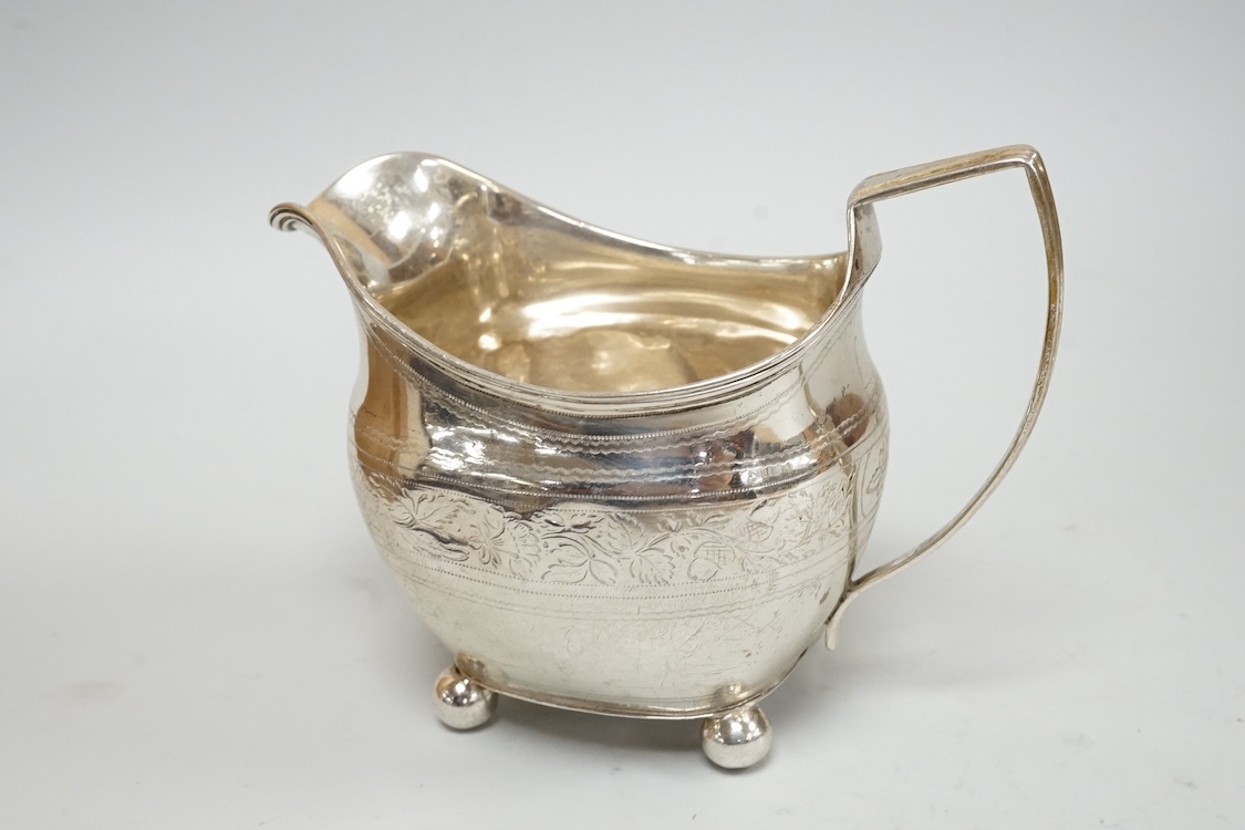 A George III silver cream jug, on four ball feet, London, 1812, 95mm, with engraved foliate band, maker's mark rubbed.